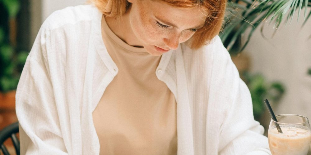 Woman analyzing financial documents using laptop and calculator indoors.